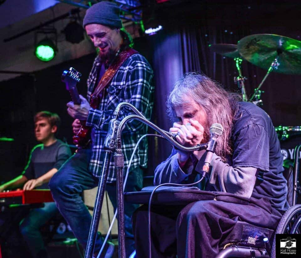 Johnny Wheels playing a harmonica solo with Brandon Logan by his side playing guitar.